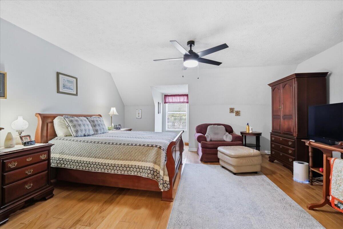 Furnished bedroom with a large wooden bed, hardwood floors, and a sitting area.