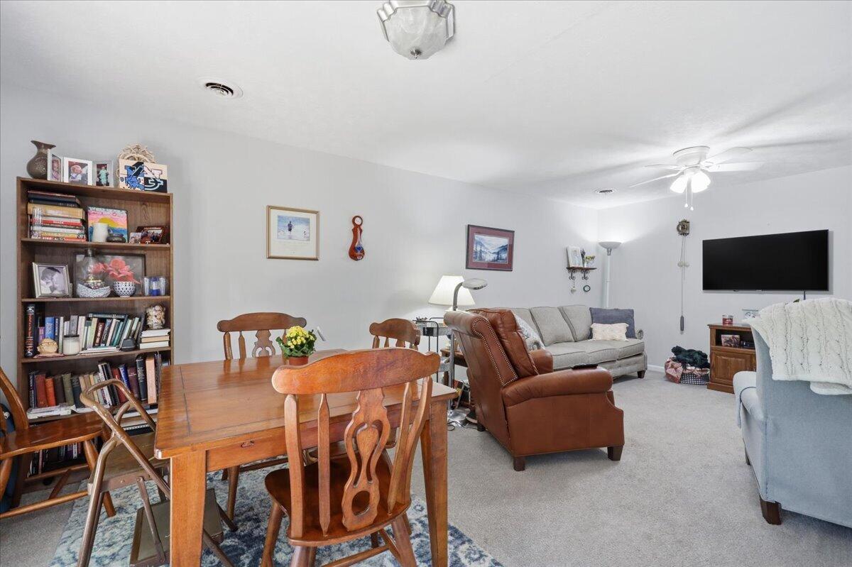 Furnished living and dining area with a wooden table, bookcase, gray sofa, and brown recliner.