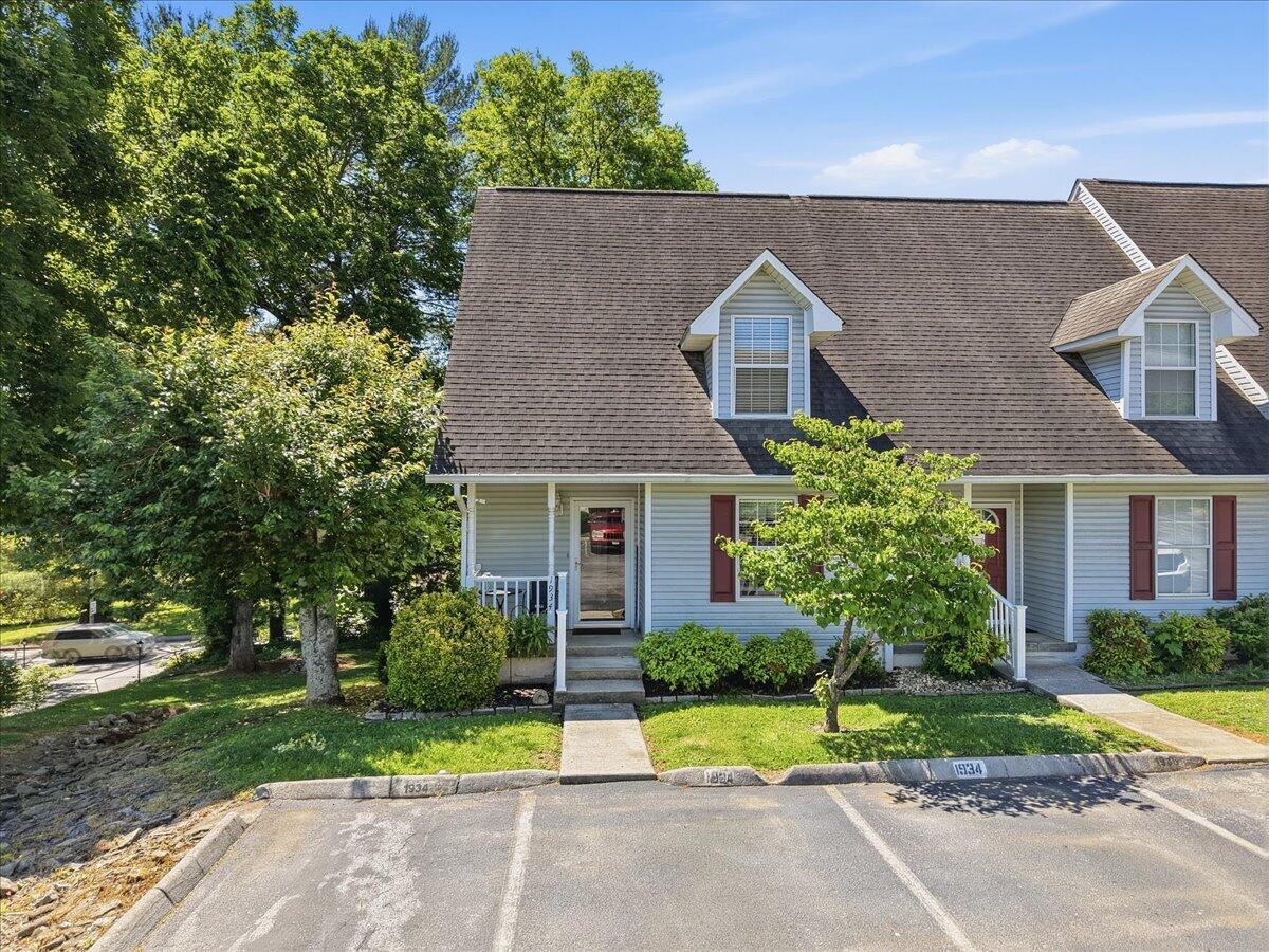 Blue-gray home with two dormers, a covered entry, and a landscaped front lawn.