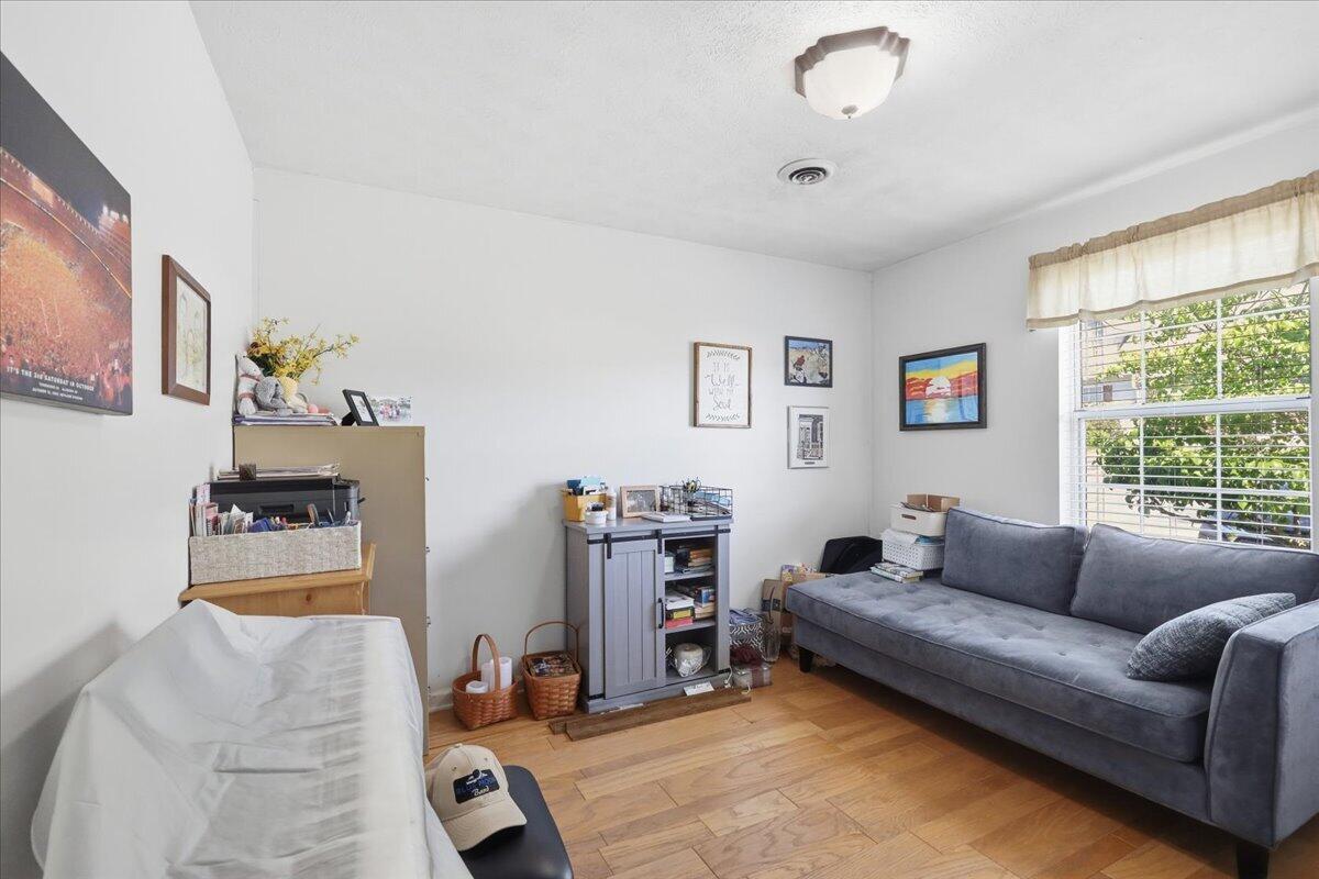 Living room with a gray sofa by a large window and hardwood floors.