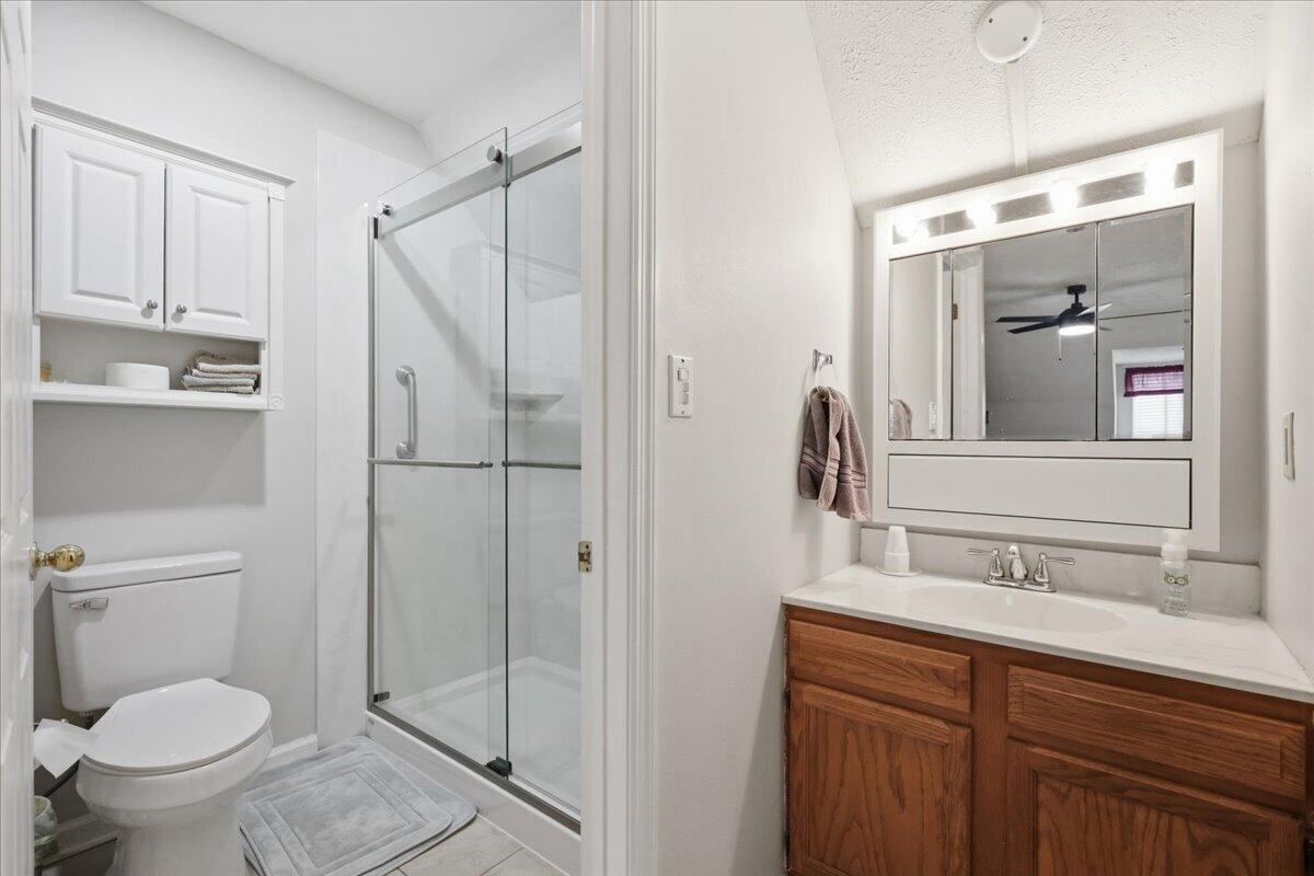 Bathroom with a glass shower, built-in storage, and a wood vanity beneath an illuminated mirror.