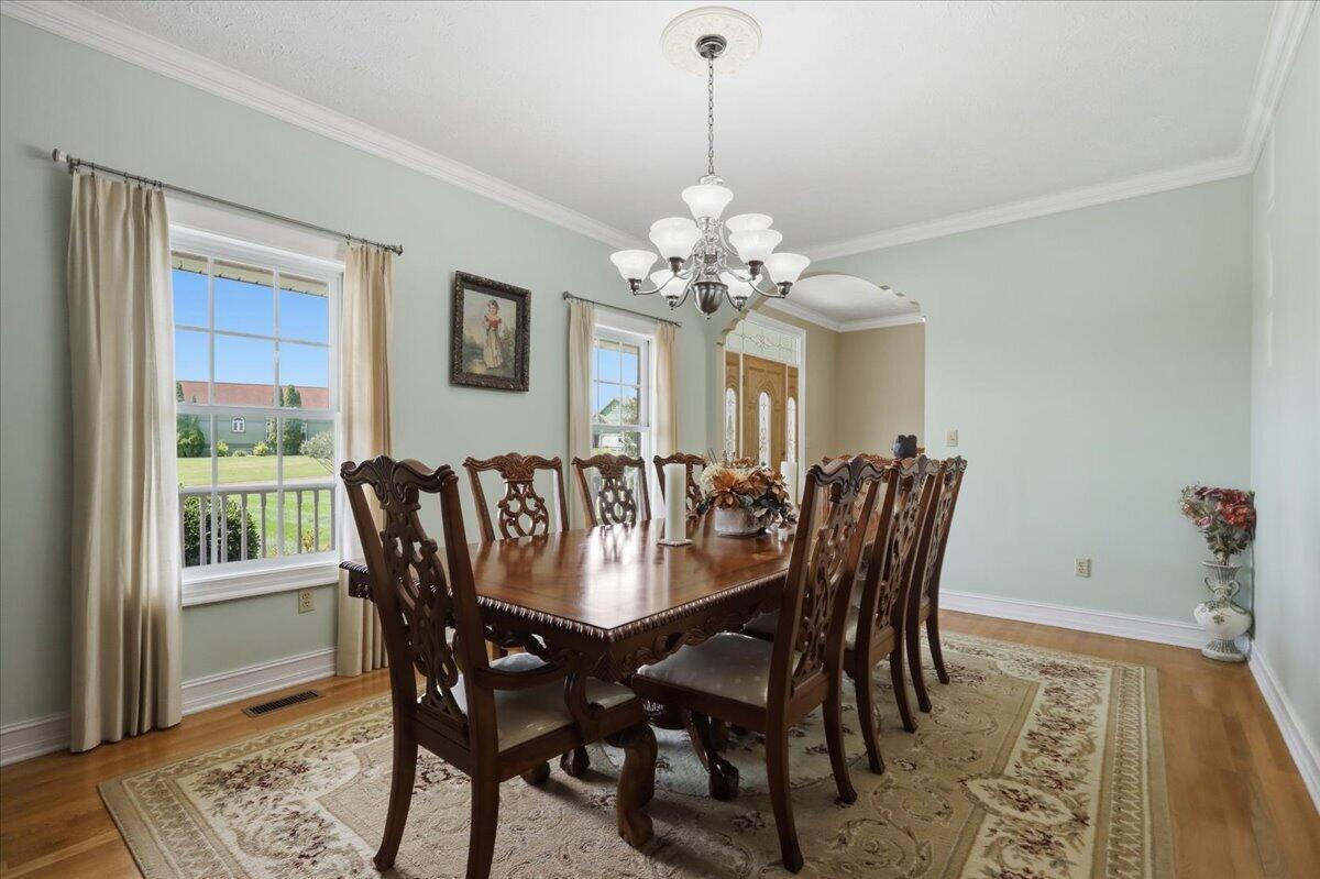 Dining room with a carved wood table and chairs beneath a chandelier.