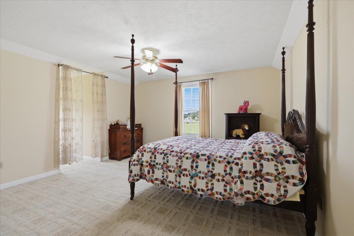 Bedroom with a dark wood four-poster bed and colorful patchwork quilt.