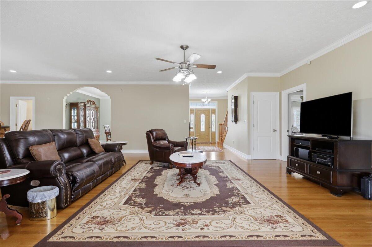Furnished living room with leather seating, a patterned rug, hardwood floors, and a television.