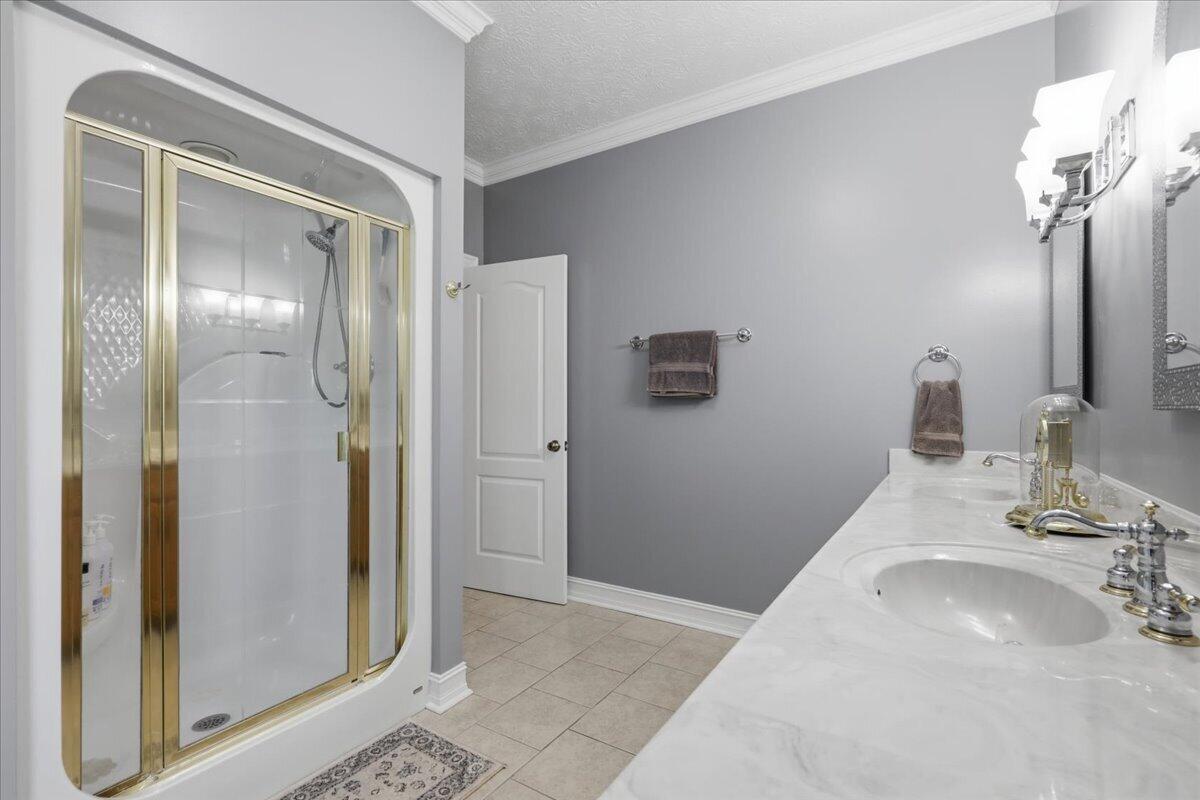 Bathroom with a gold-framed glass shower and a long white vanity.