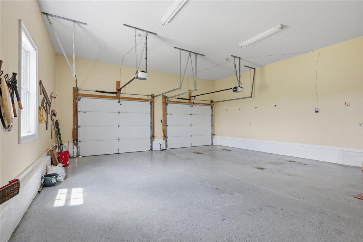 Spacious two-car garage with closed overhead doors, a concrete floor, and a window.