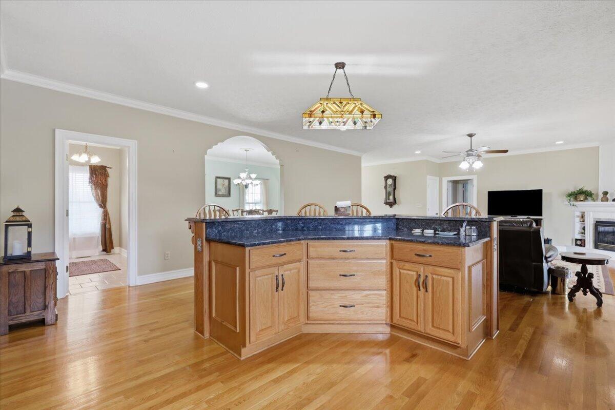 Kitchen with a large wood island, dark blue countertop, and hardwood floors opening to the living room.