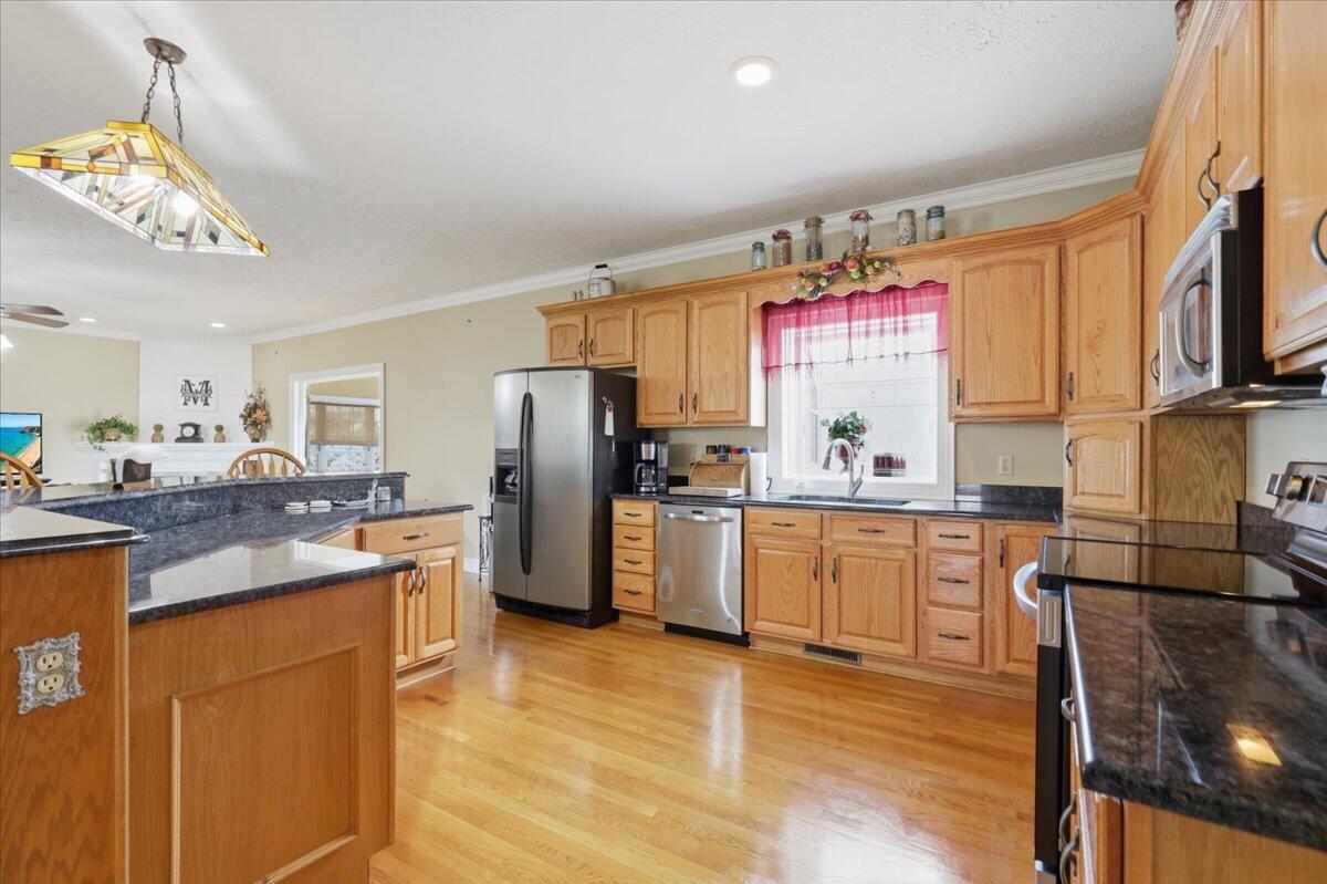 Kitchen with wood cabinetry, granite counters, stainless steel appliances, and hardwood floors.
