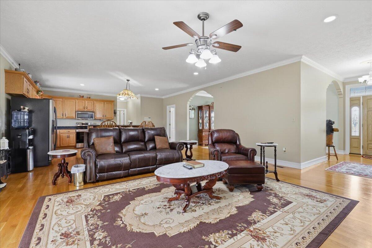 Living room with leather seating, a large patterned rug, hardwood floors, and an open kitchen.