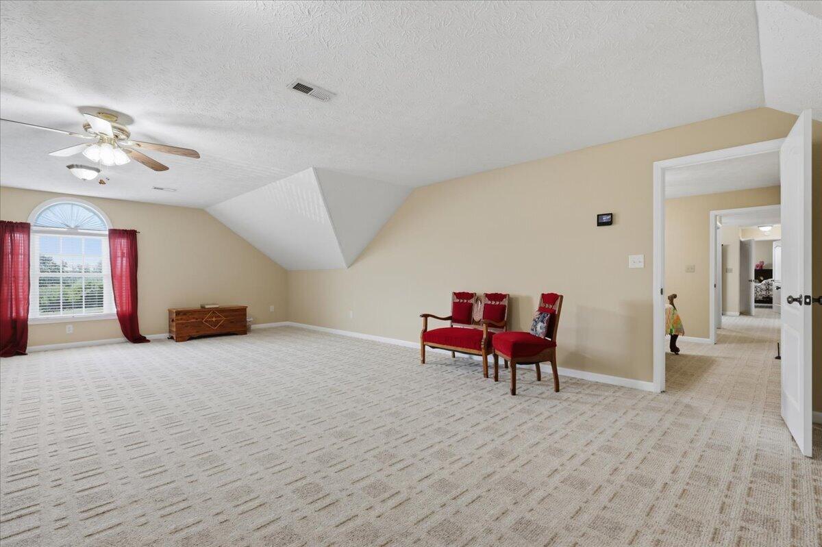 Carpeted upper-level room with an arched red-curtained window and red chairs.