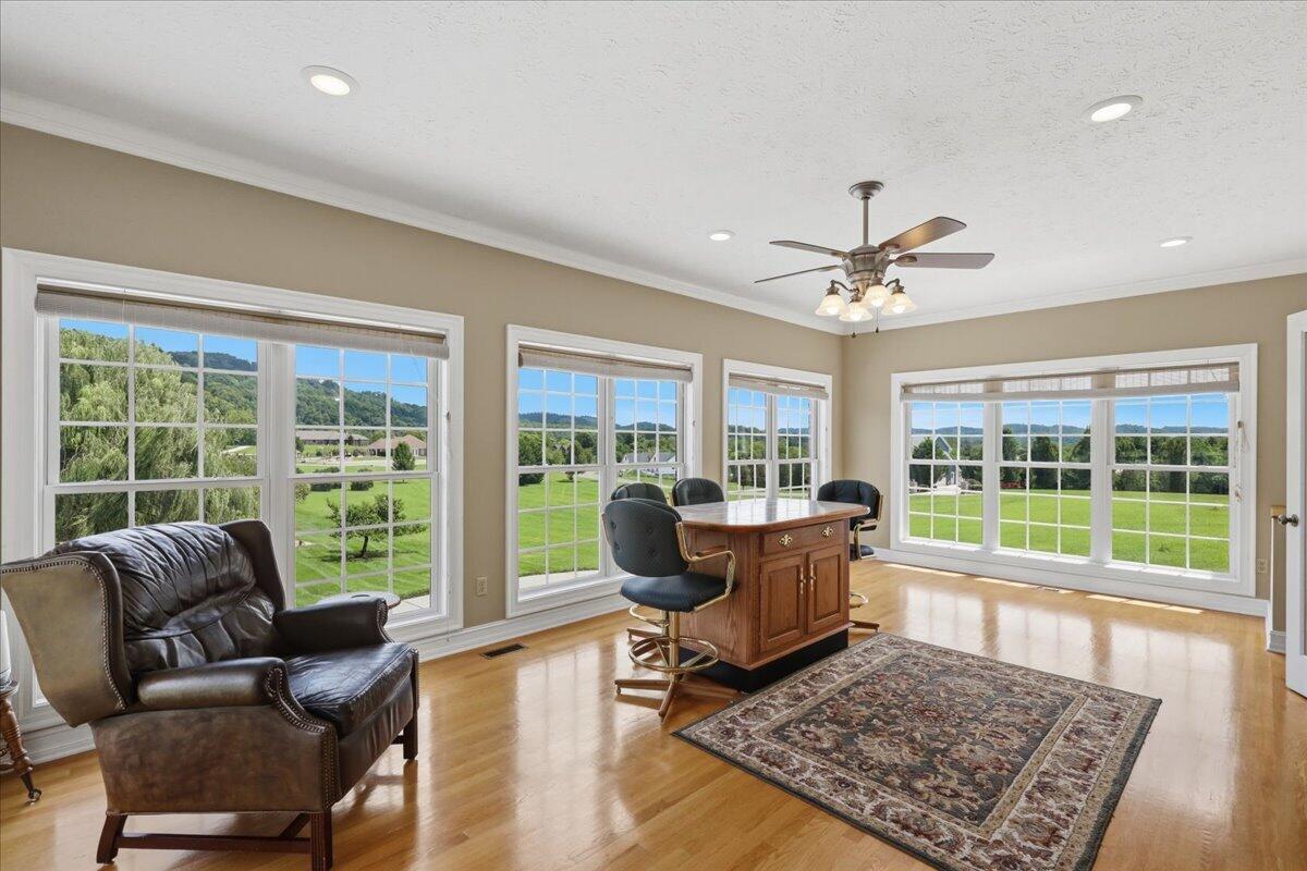 Dining area with broad windows overlooking green lawns and wooded hills.