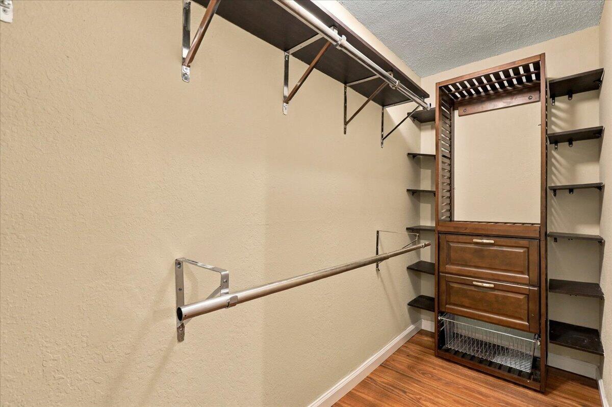 Walk-in closet with built-in wood drawers, shelving, and hanging rods.