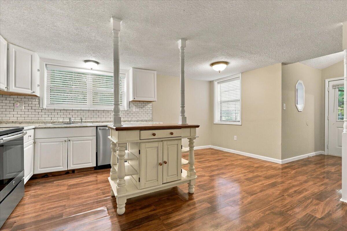 Kitchen with white cabinets, subway tile backsplash, and a freestanding island with a dark wood top.