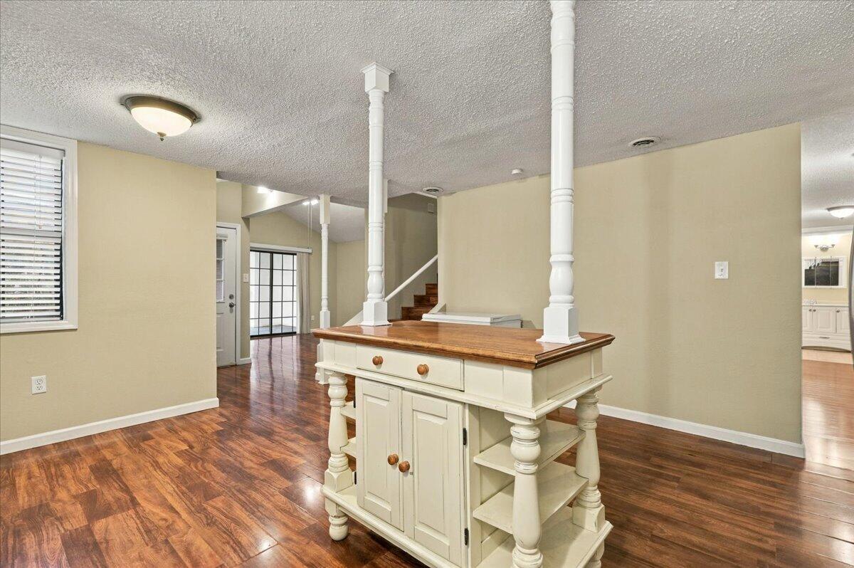 Open kitchen with a white island topped in butcher block and dark wood flooring.