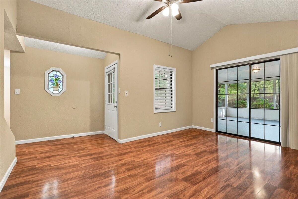 Empty room with glossy hardwood floors and sliding glass doors to a screened porch.