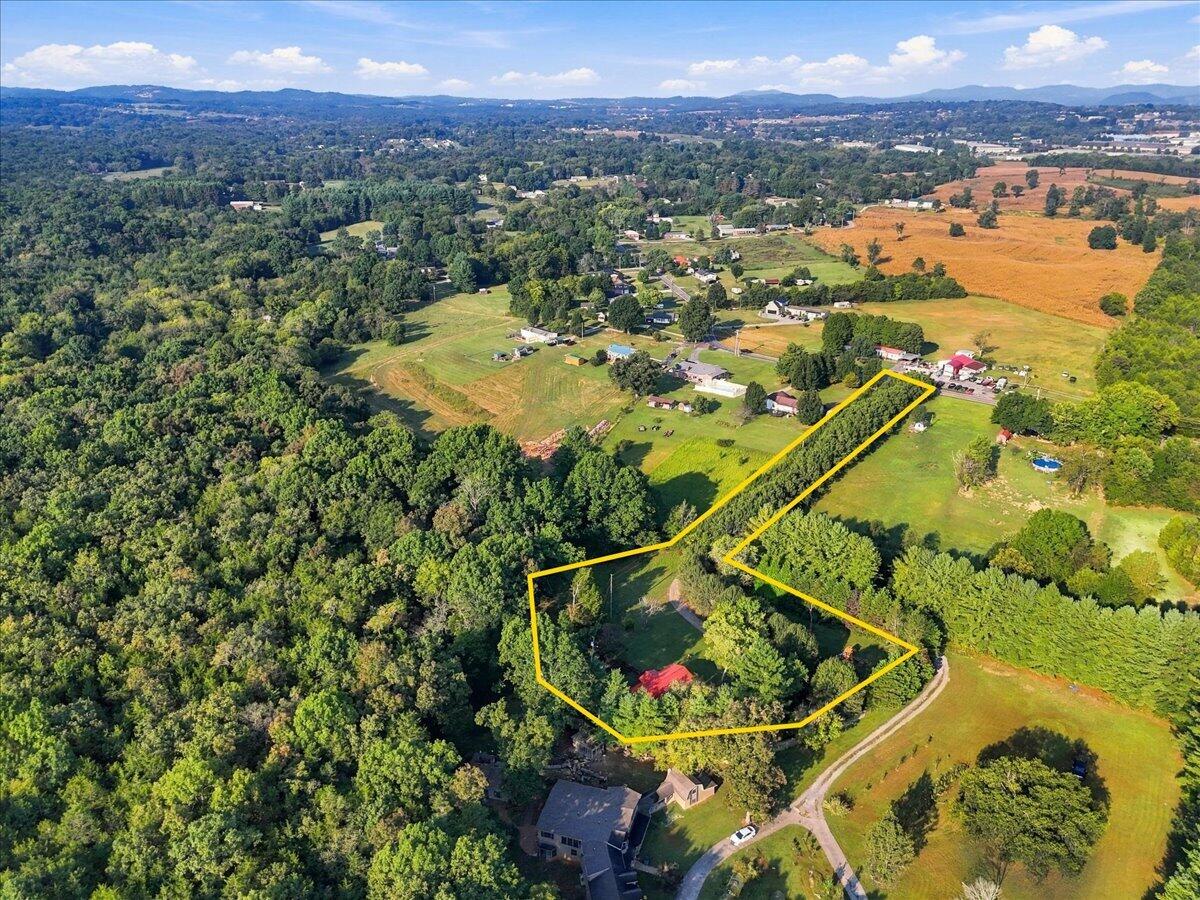 Aerial view of yellow-outlined wooded acreage and a narrow tree-lined extension amid rural fields.