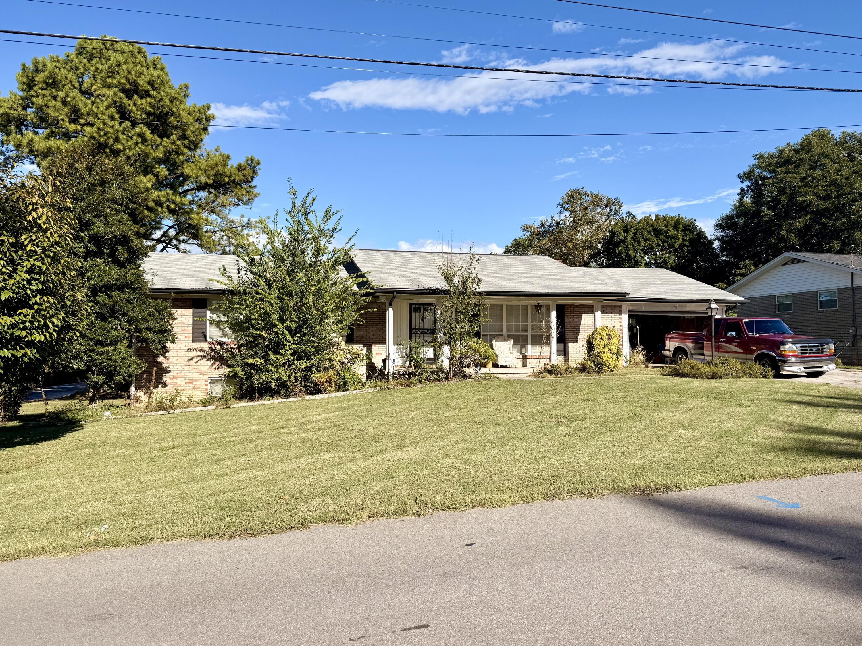 Single-story brick home with a covered porch, broad lawn, and red pickup truck in the driveway.