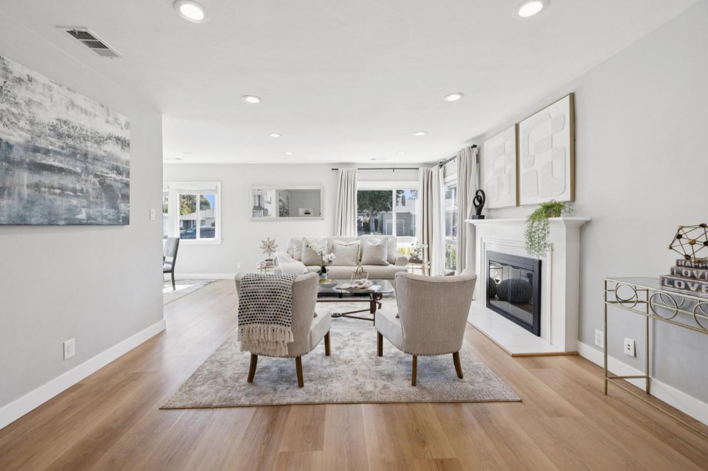 Staged living room with a white fireplace, neutral seating, and light wood floors.