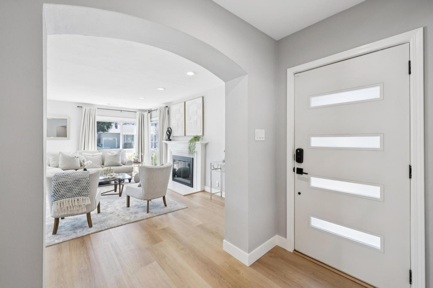 Entryway with a glass-panel front door opening to a bright living room with a fireplace.