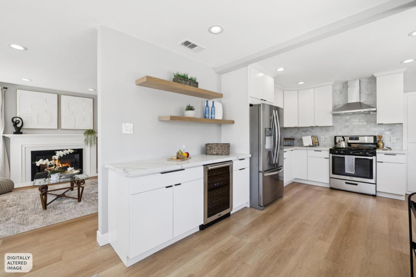 Bright white kitchen with stainless steel appliances, a wine cooler, and an adjoining living area with a fireplace.