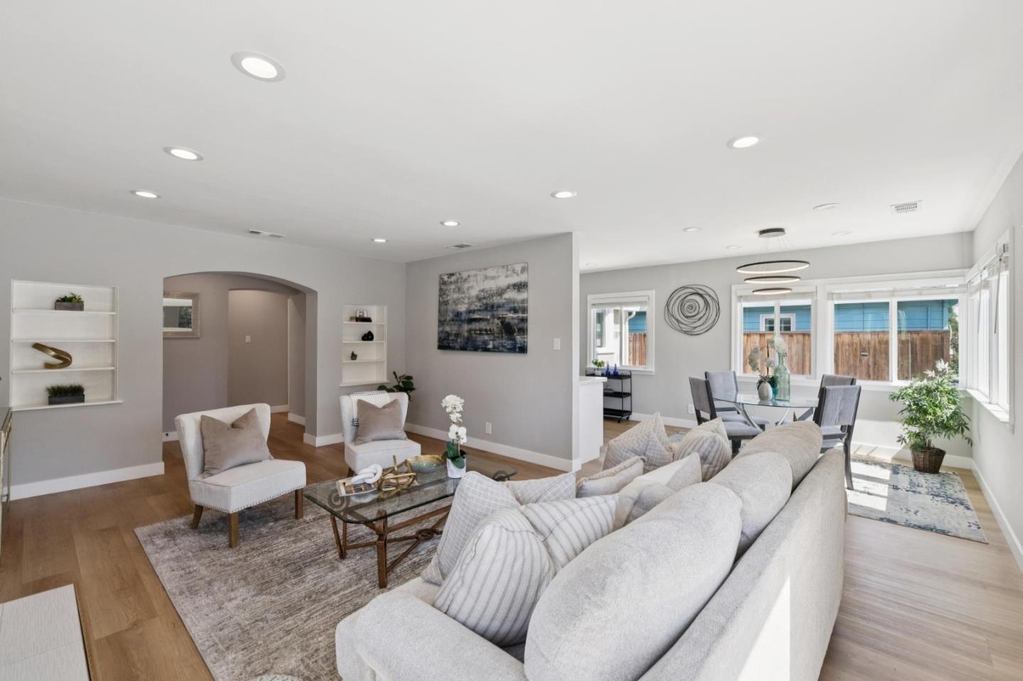 Open-plan living room with a large sectional sofa, armchairs, and dining area beside wide windows.