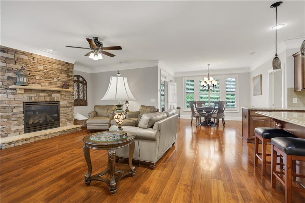 Living room with a stone fireplace, hardwood floors, and an adjoining dining area.