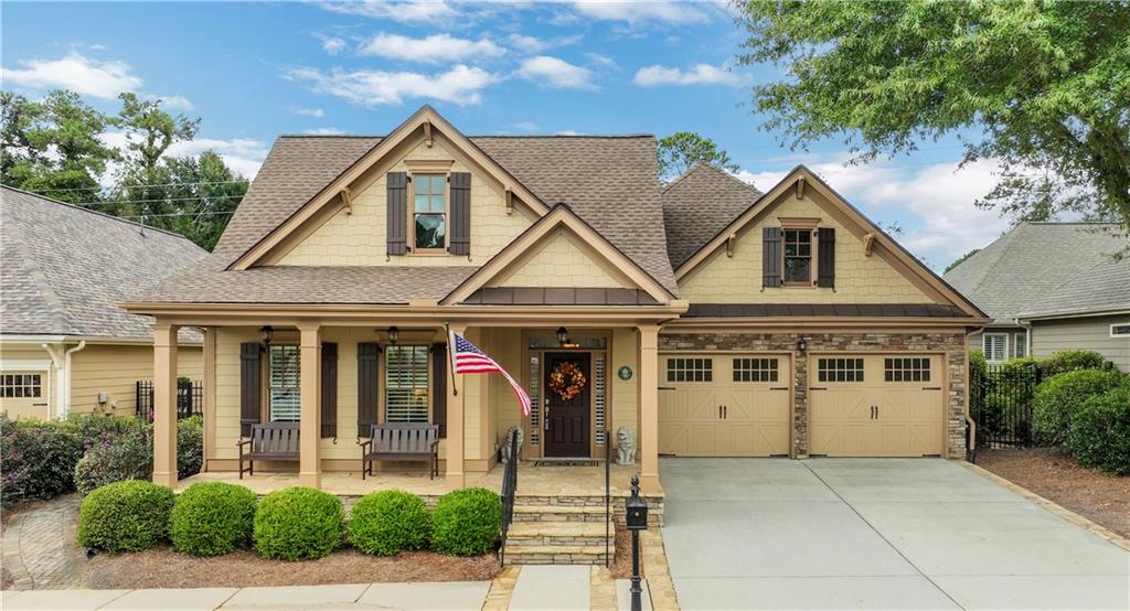 Beige two-story house with a covered porch, double garage, and American flag.