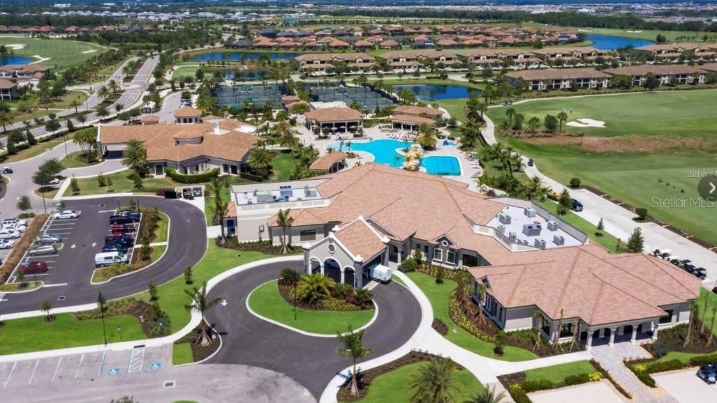 Aerial view of a residential community clubhouse, pools, tennis courts, and golf course.