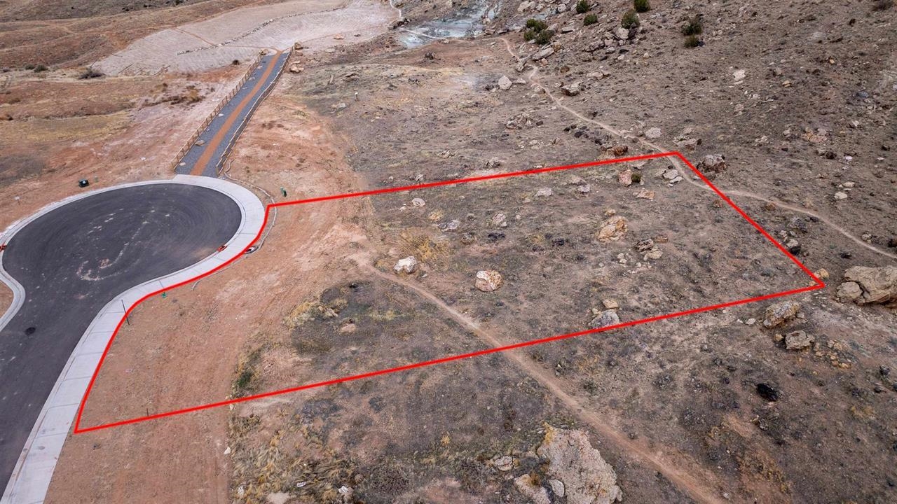 Vacant rocky lot outlined in red beside a paved cul-de-sac.