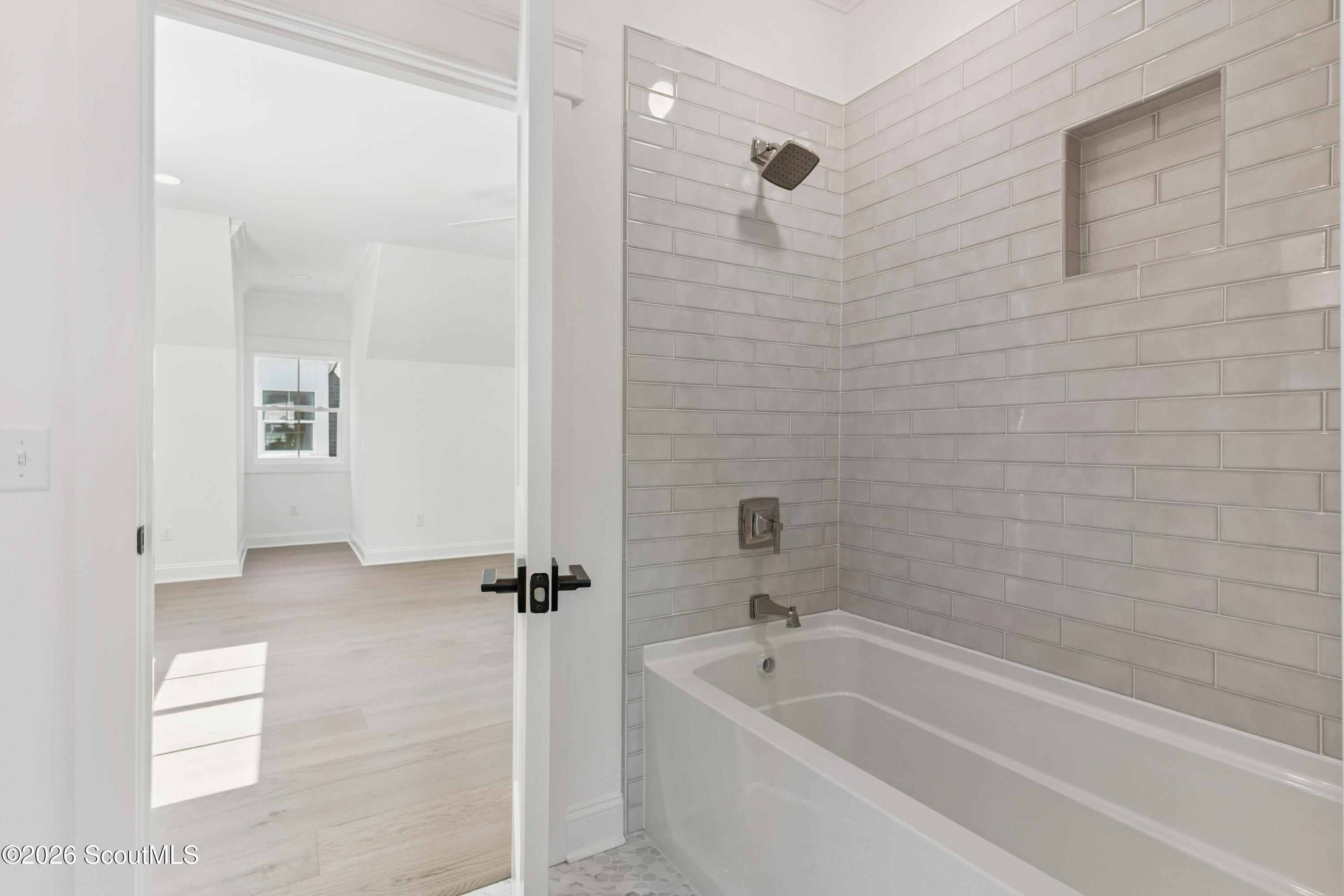 Bathroom with a white tub, gray subway-tile surround, and recessed shower niche.