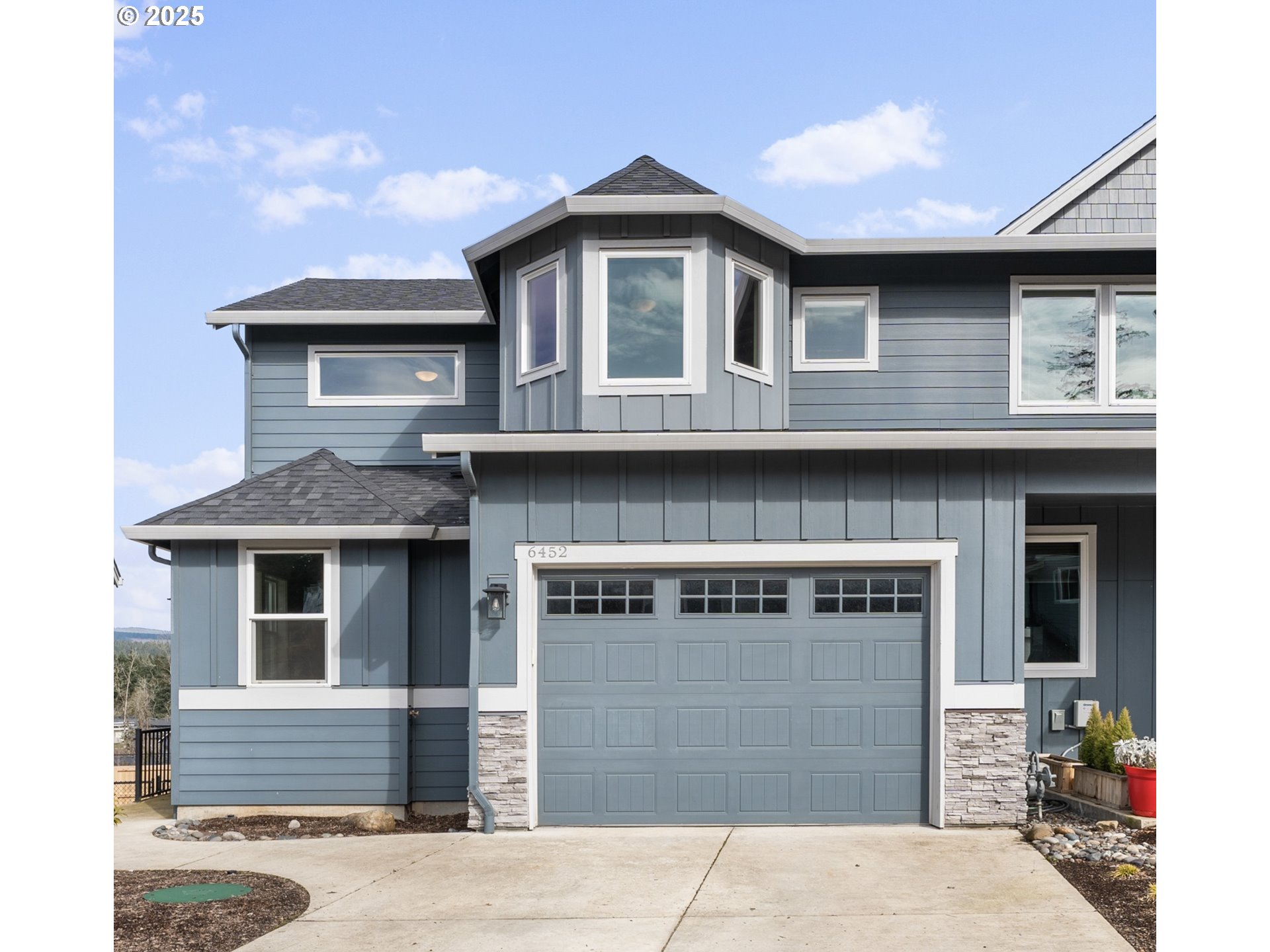 Blue-gray two-story home with white trim, stone accents, and a prominent front garage.