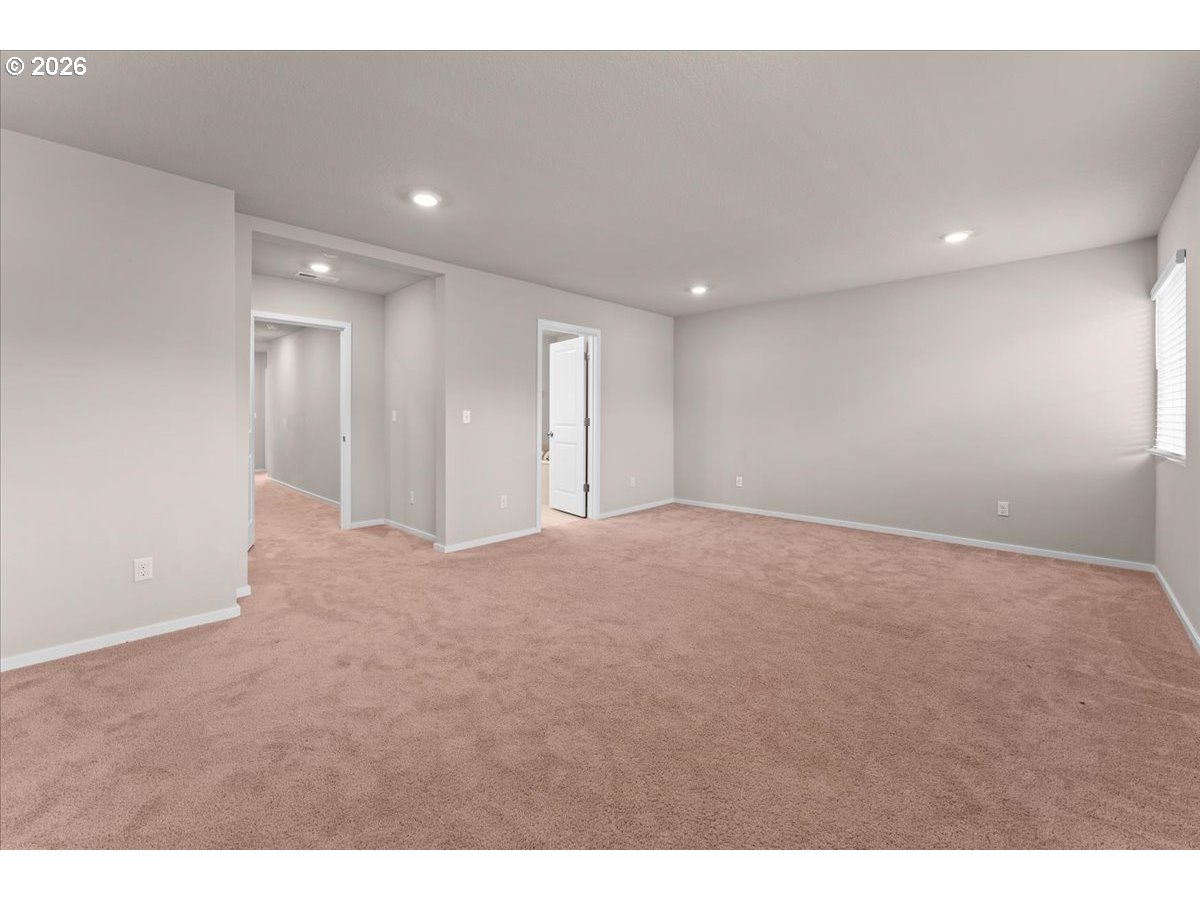 Unfurnished carpeted room with recessed lights, a window with blinds, and two open doorways.
