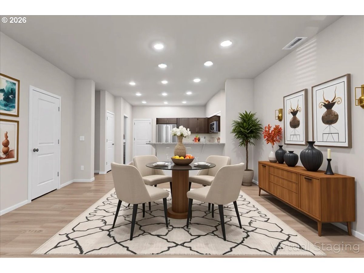 Staged dining area with a round table and chairs beside an open kitchen.