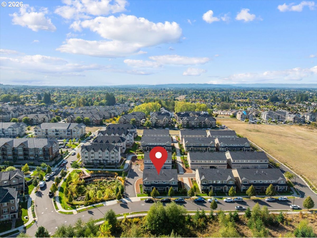 Aerial view of attached homes and neighborhood streets, with a red map pin marking a home near the foreground.