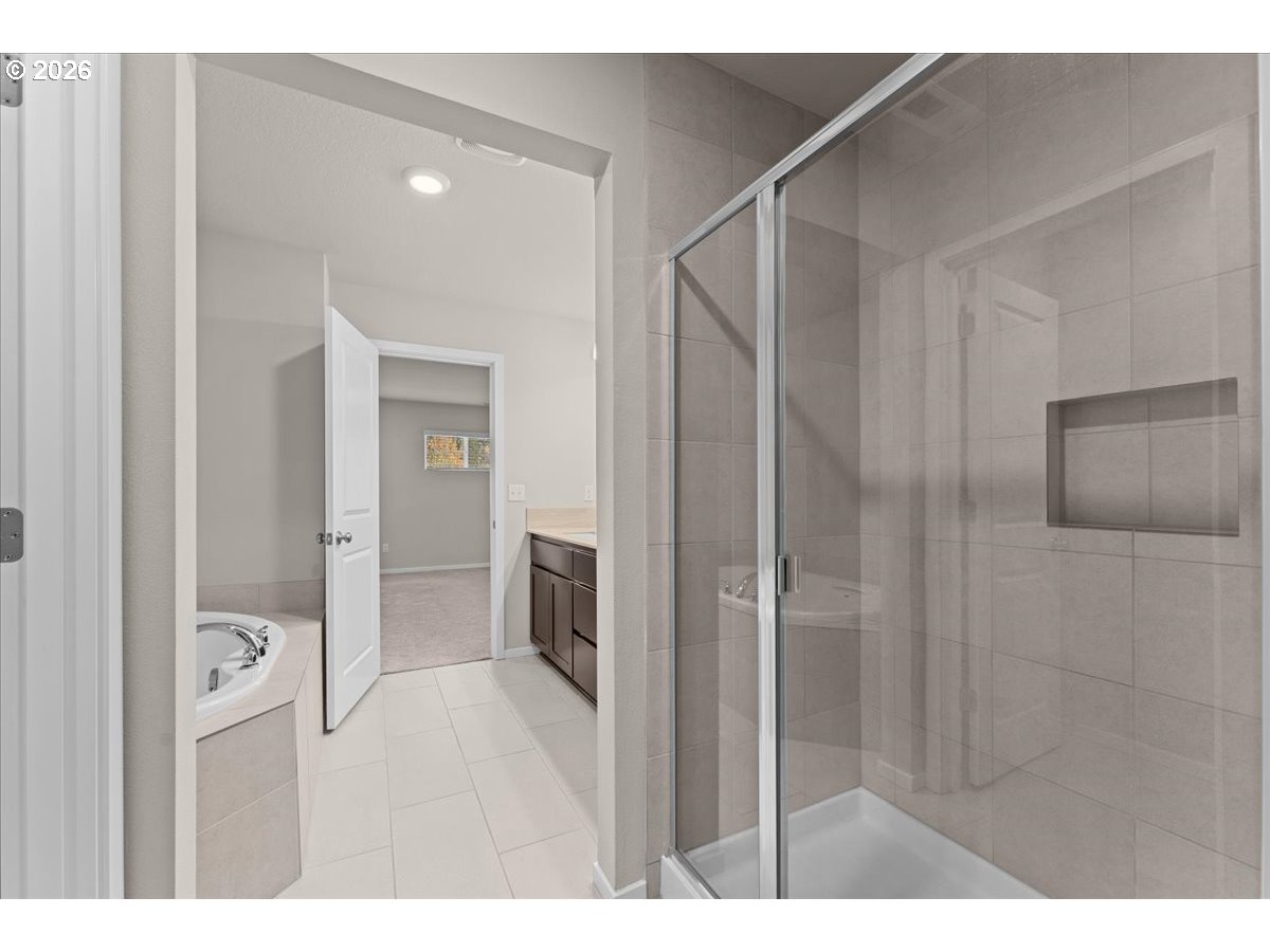 Bathroom with a glass-enclosed tiled shower, soaking tub, and dark wood vanity.