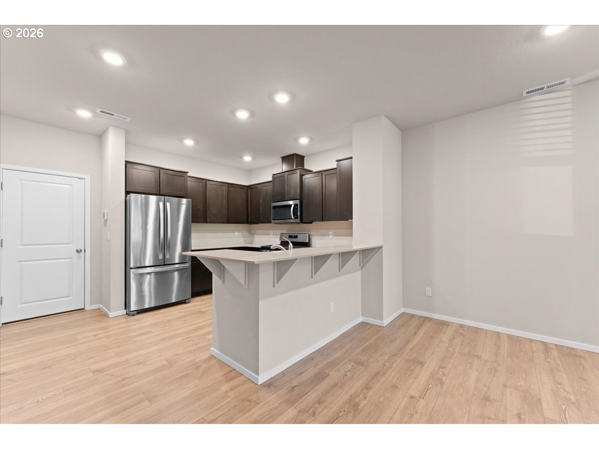 Kitchen with dark cabinets, stainless steel appliances, and a white peninsula counter.