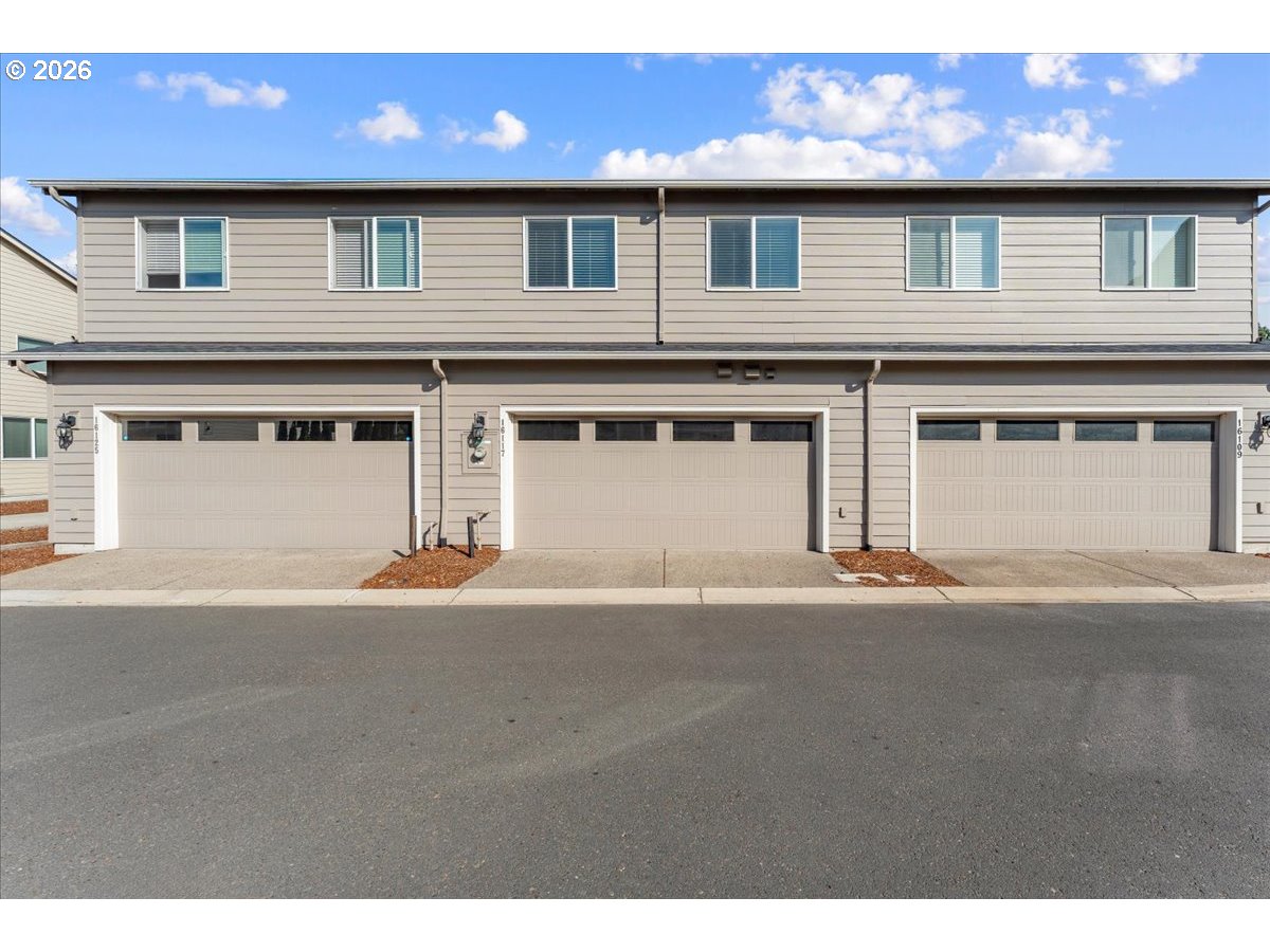Gray two-story townhome facade with three white garage doors and upper-floor windows.
