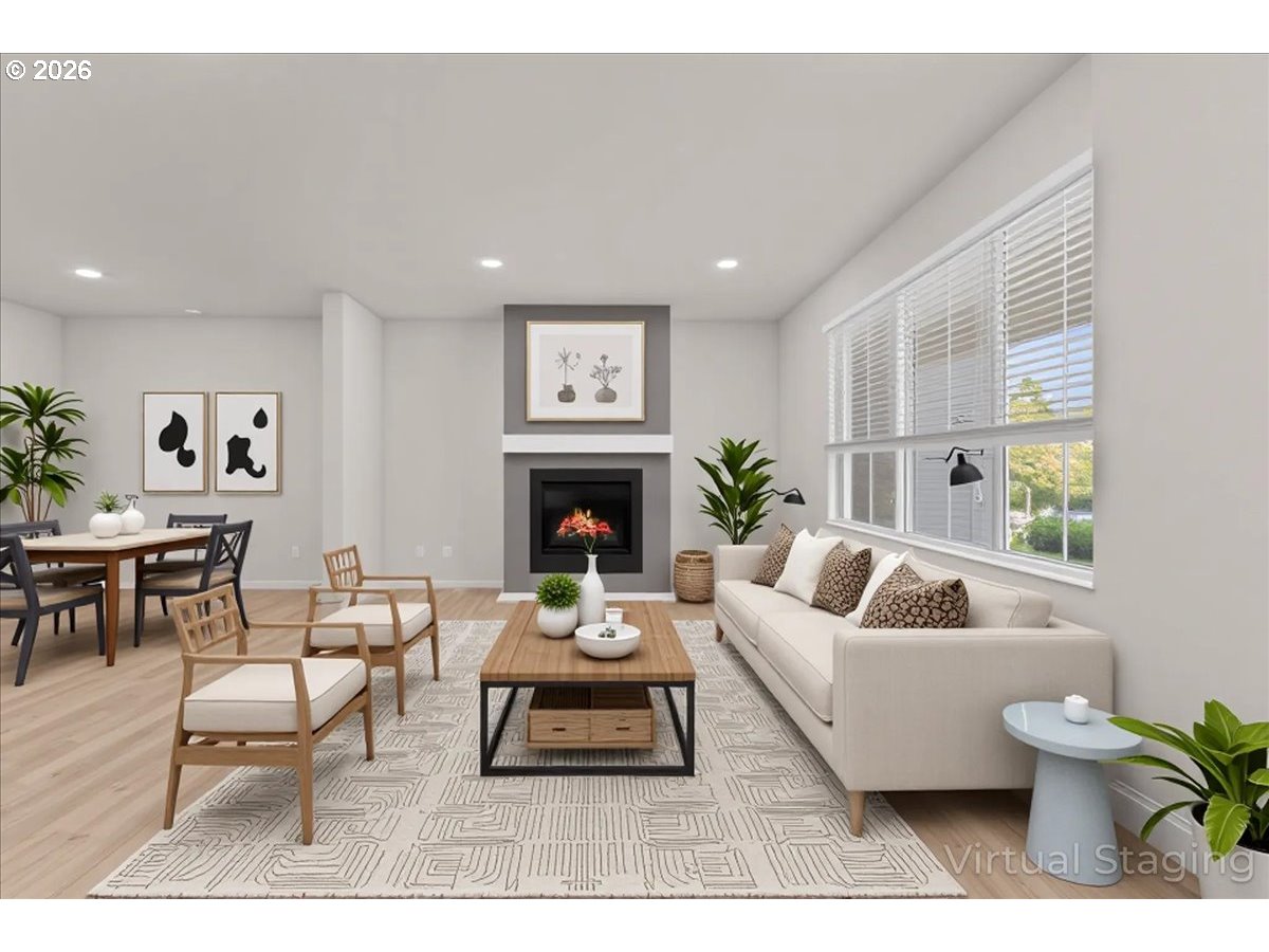 Virtually staged living room with fireplace, large windows, and adjoining dining area.