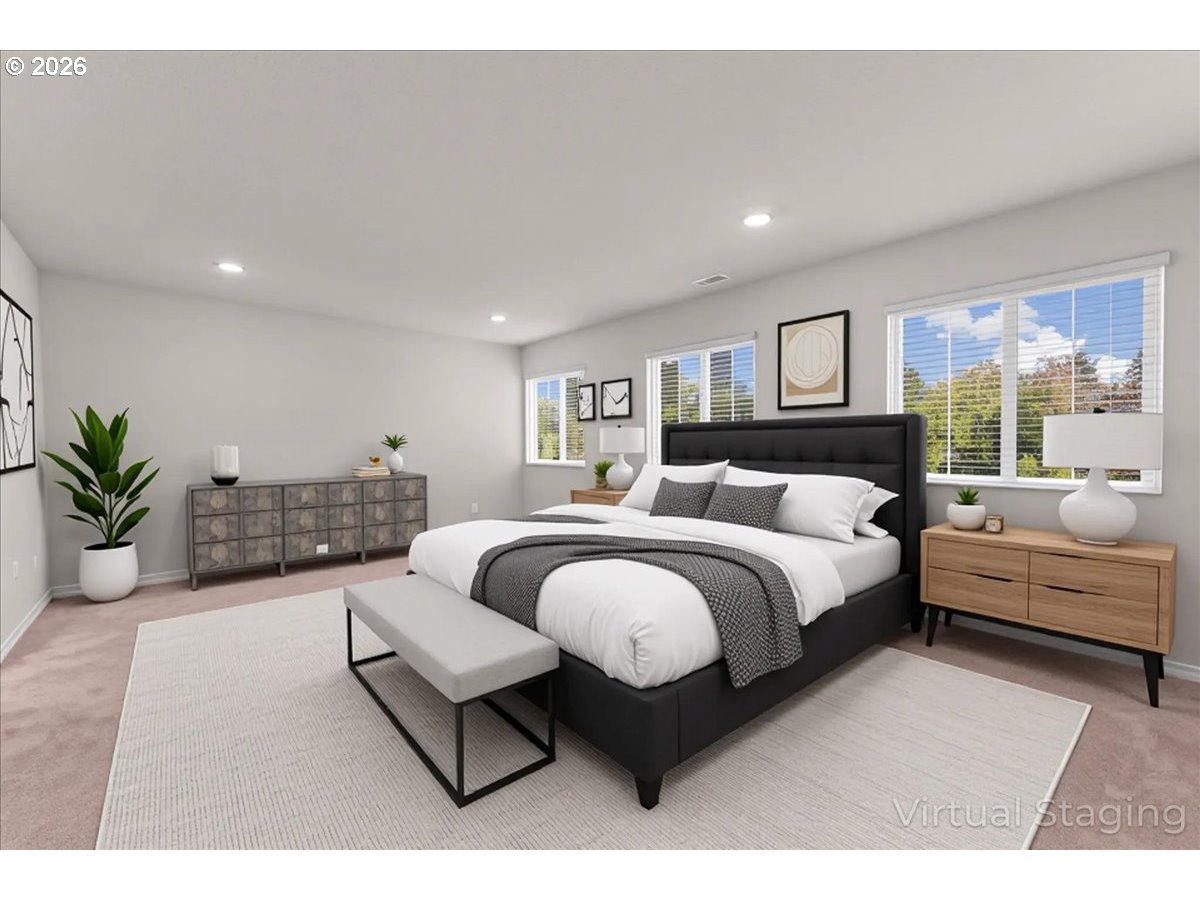 Virtually staged bedroom with a large bed, dark gray headboard, white bedding, and windows overlooking greenery.