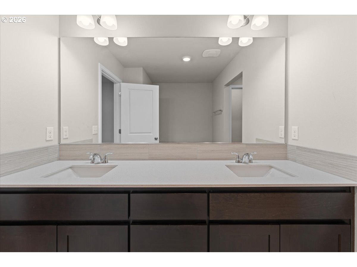 Bathroom vanity with two sinks, a wide mirror, and dark wood cabinetry.