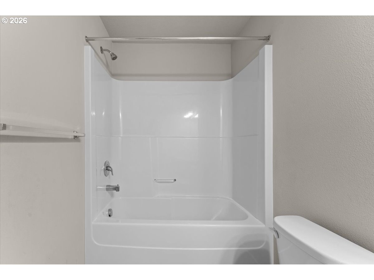 White bathtub and shower alcove with chrome fixtures and a built-in soap dish.