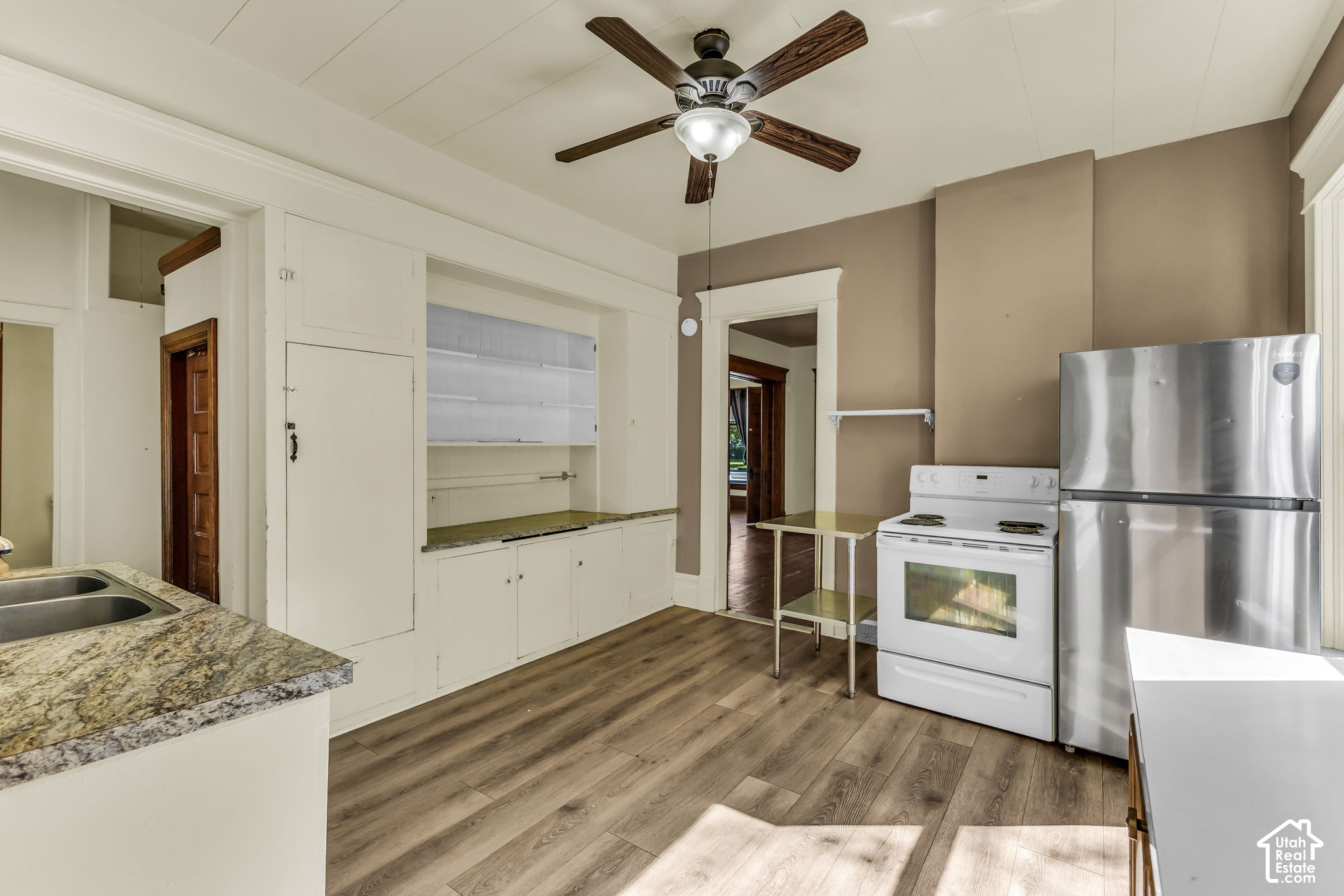 Kitchen with white built-in cabinets, granite counter, electric stove, and stainless-steel refrigerator.