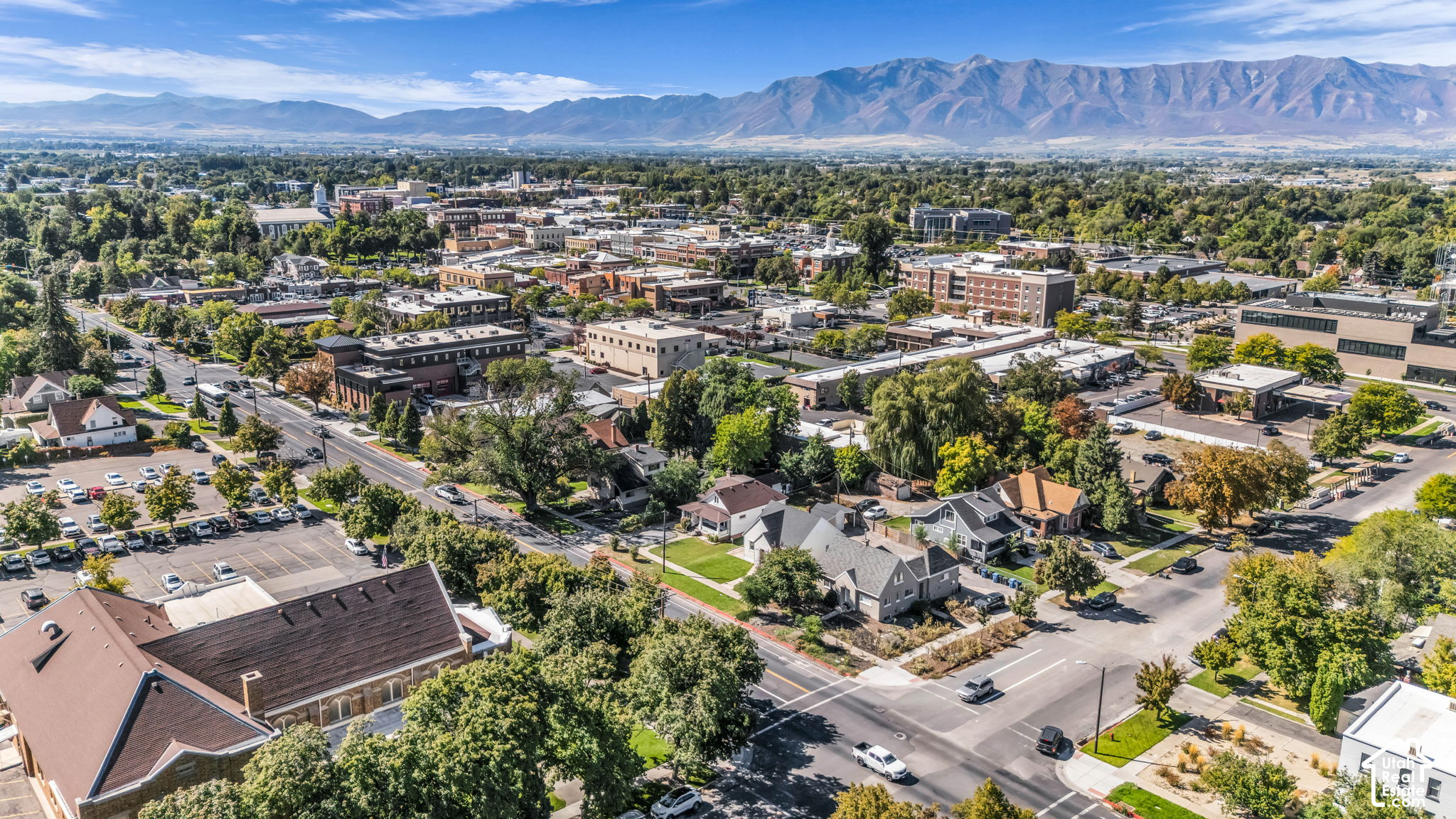 Aerial view of downtown Logan and surrounding neighborhoods, with a mountain range stretching across the horizon.