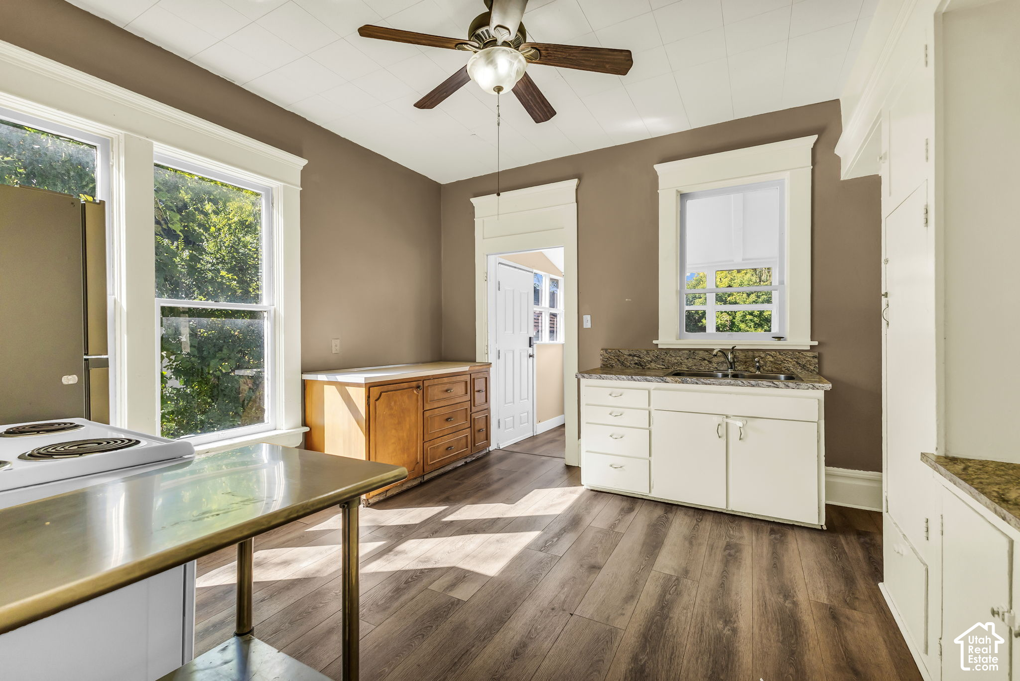 Kitchen with white cabinetry, granite counters, large windows, and dark plank flooring.
