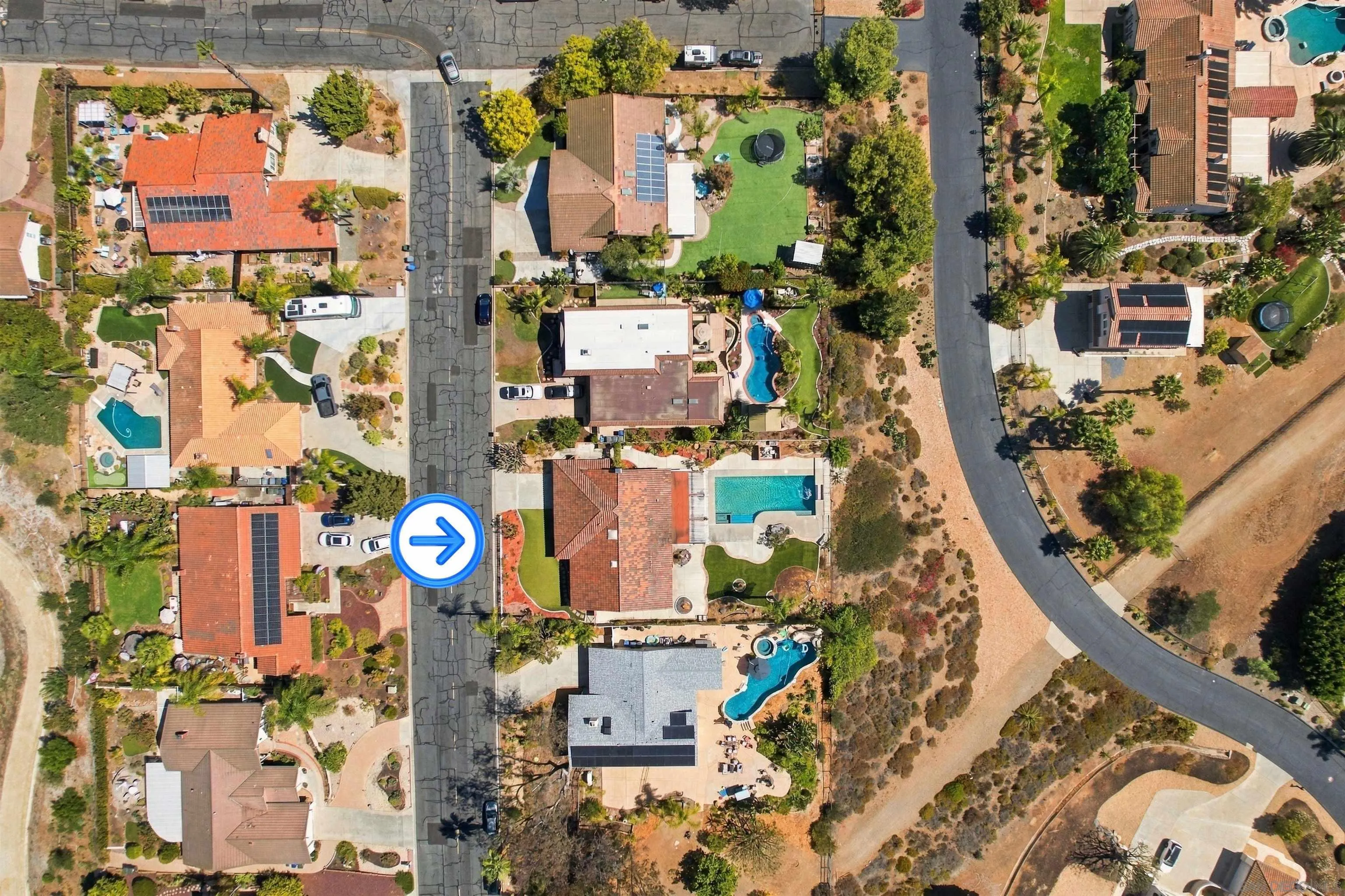 Aerial view of the home and neighborhood, with an arrow marking the home beside its pool and landscaped yard.
