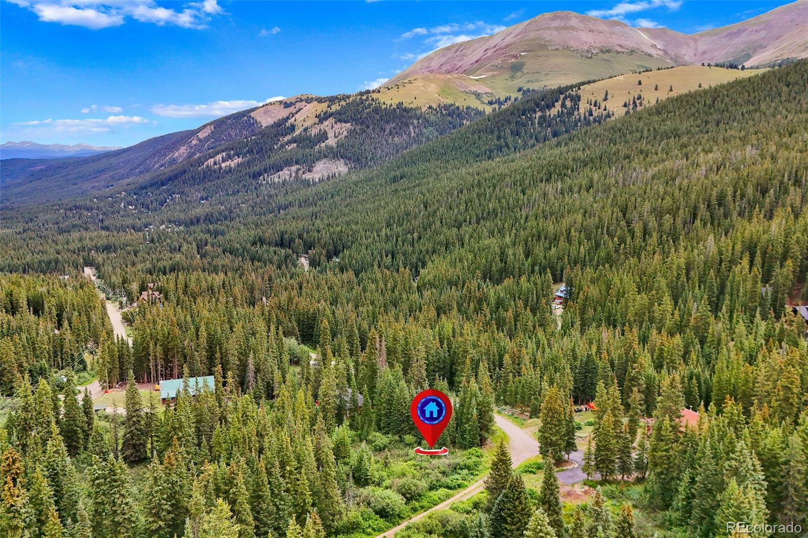 Aerial view of forested mountain acreage, marked by a pin beside a winding road.