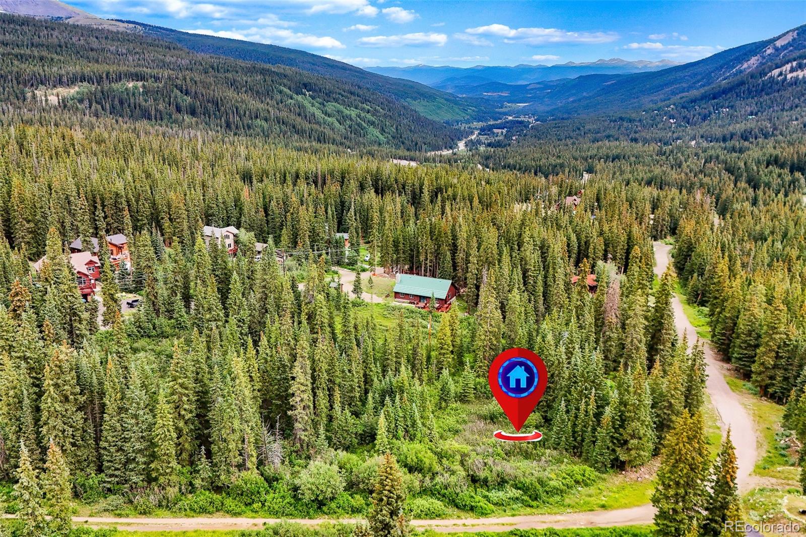 Aerial view of a forested mountain property, with a red location pin marking a clearing.