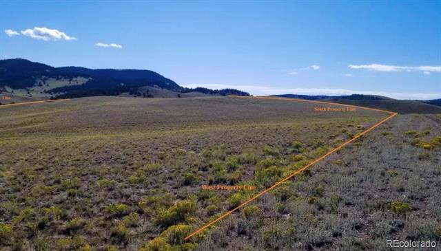 Aerial view of open scrubland property marked by orange boundary lines, with low mountains in the distance.