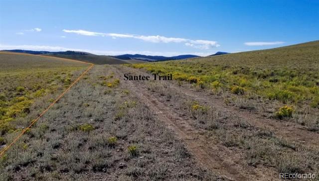 Open scrubland with a dirt track and distant mountain ridges.