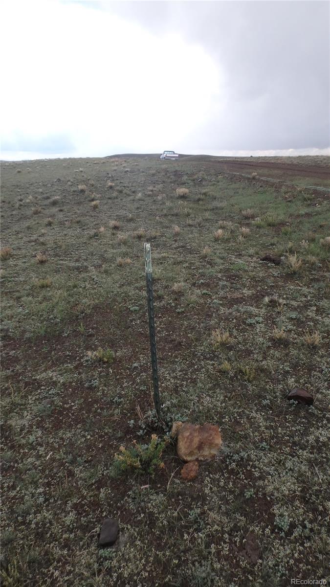Open rocky hillside with sparse vegetation, a survey marker, and a dirt track near the ridge.